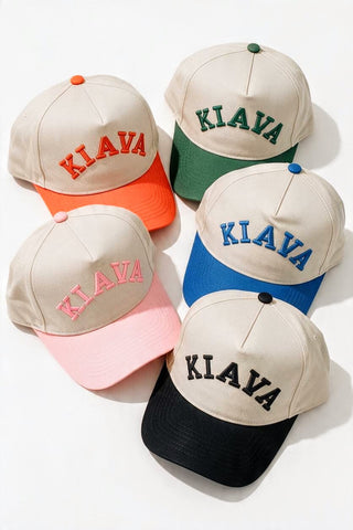 Five baseball caps arranged on a white background, each in a different color combination: beige with red, green, pink, blue, and black visors, all with the word 'KIAYA' embroidered on the front.
