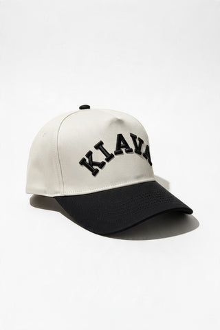 A baseball cap with an off-white crown and a black curved brim, featuring the word 'KIAYAN' embroidered in black arched letters across the front. The cap is photographed on a clean white background with a soft shadow.